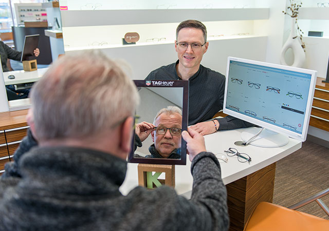 ein optiker beraet einen kunden beim kauf einer brille