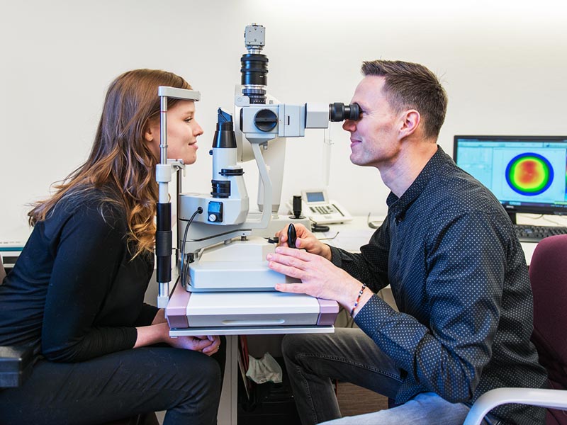 optiker schaut sich die augen einer kundin beim eventfotoshooting an